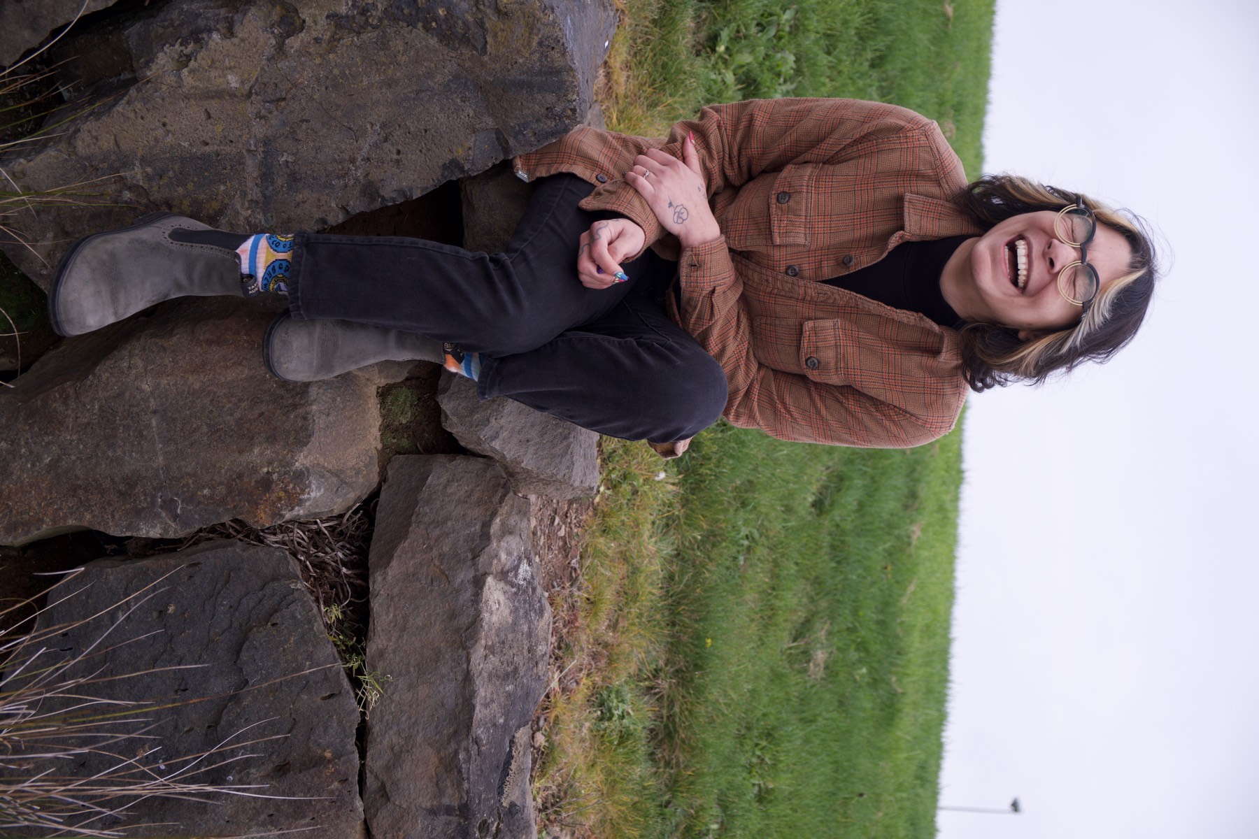 Jessica Salas sitting outdoors on rocks and laughing.